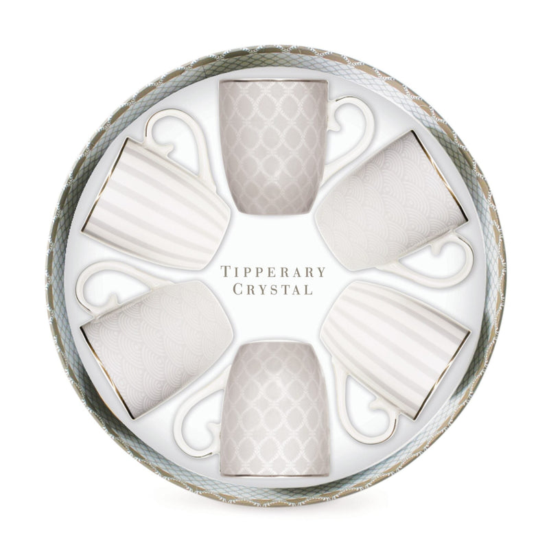 A circular gift box containing six white ceramic cups arranged in a circle, with the words 'Tipperary Crystal' printed in the center. The cups are white with subtle gray and gold patterns and borders, set against a clean white background.